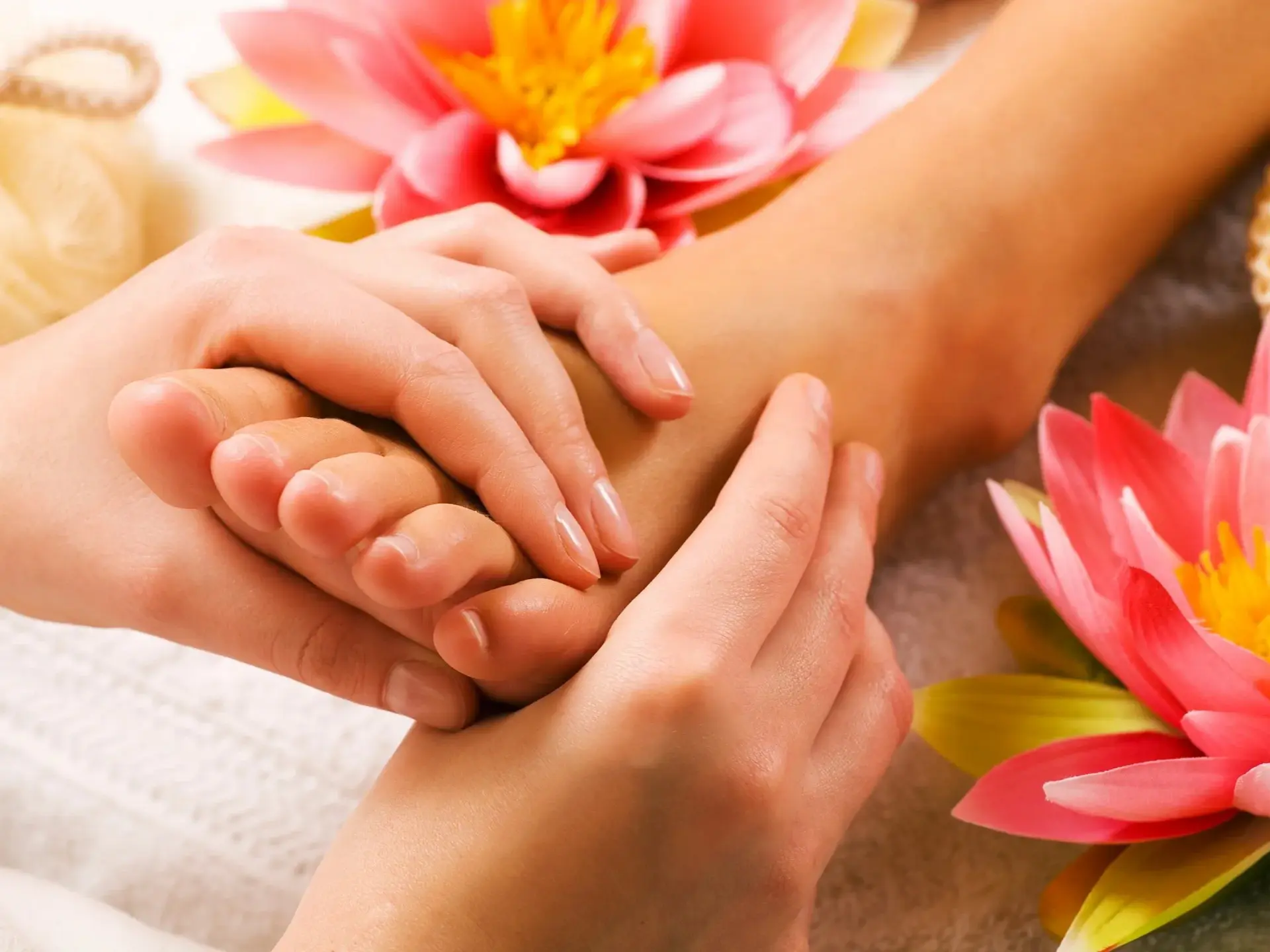 Hands massaging foot near pink flowers