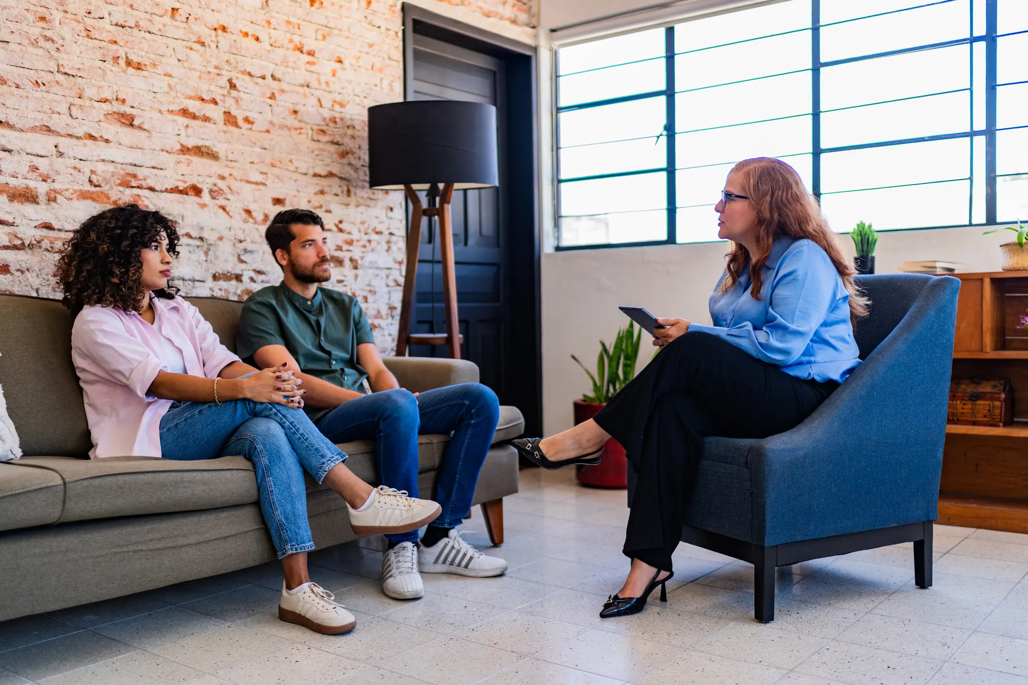 Three people engaged in a discussion in a modern office setting.